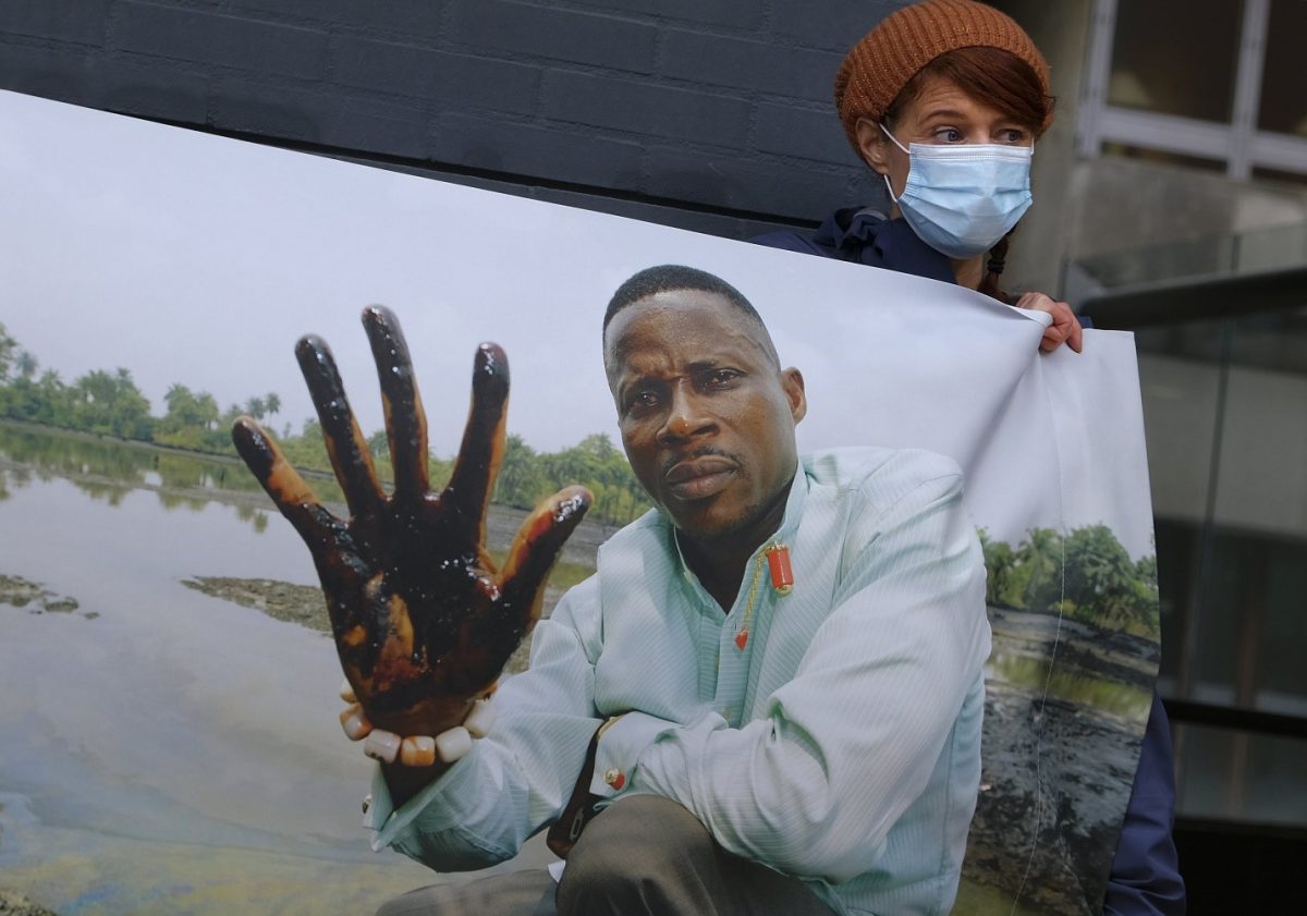 Friends of the Earth supporters unfold a banner outside the district court in The Hague, Netherlands, Friday, Jan. 29, 2021, where the court is delivering its judgment in a long-running case in which four Nigerian farmers are seeking compensation and a cleanup from energy giant Shell for pollution caused by leaking oil pipelines in the Niger Delta. (AP Photo/Mike Corder)