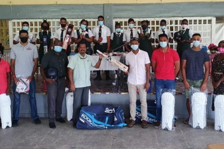 Former Guyana and West Indies cricketer Shivnarine Chanderpaul (fifth from right) presents a bat to Headmaster of the West Demerara Secondary School, Harrinarine. Sharing the moment are teachers and students of the school and cricketers Tagenarine Chanderpaul (third right) and Akshaya Persaud (fourth right) and local alumni representative Naveed Ali (third left)