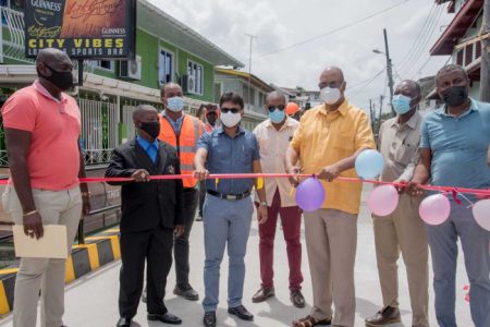 The Minister of Public Works, Juan Edghill (at centre) accompanied by the Georgetown Mayor Ubraj Narine (left of the Minister) as the Minister cuts the ribbon to mark the operation of the Sussex and Hogg streets bridge (Department of Public Information (DPI) photo)