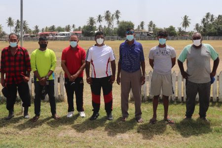 Newly elected president of Port Mourant Cricket Club, Omeshwar Sirikishun (centre) surrounded by members of the new executive with the historic ground in the background (Romario Samaroo photo)