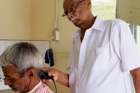Ramsaran Moonsammy cutting his son's hair.