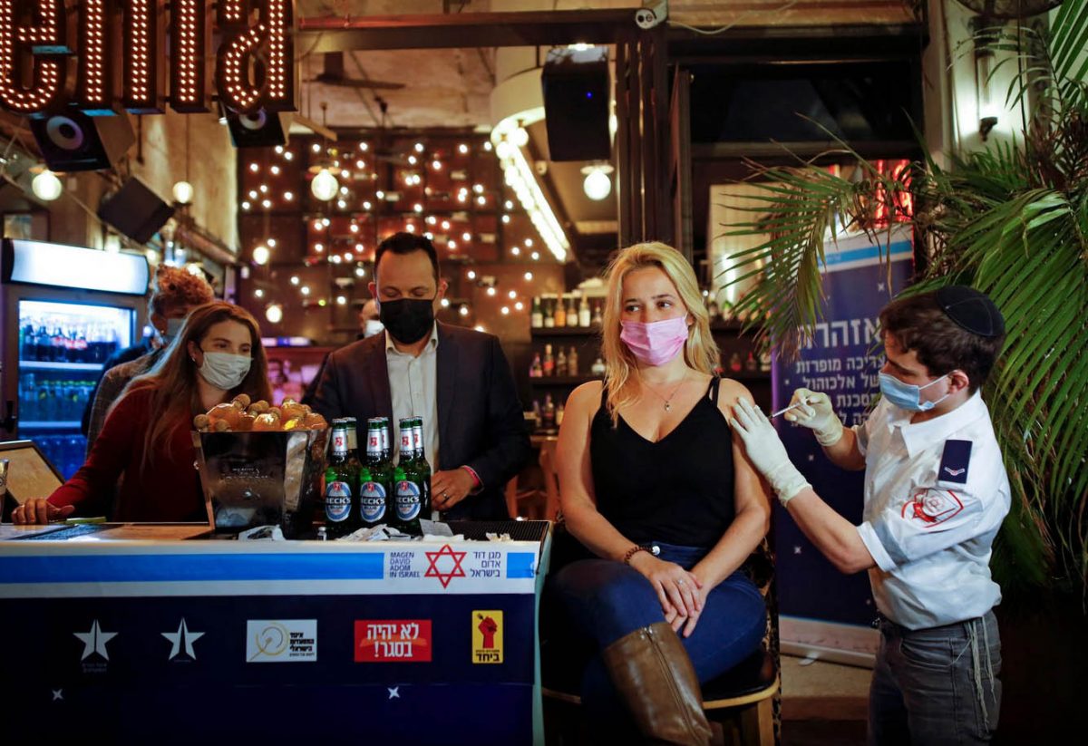 A woman receives a vaccination against COVID-19 as part of a Tel Aviv municipality initiative offering free drinks to residents getting a shot. (REUTERS/Corinna Kern photo)