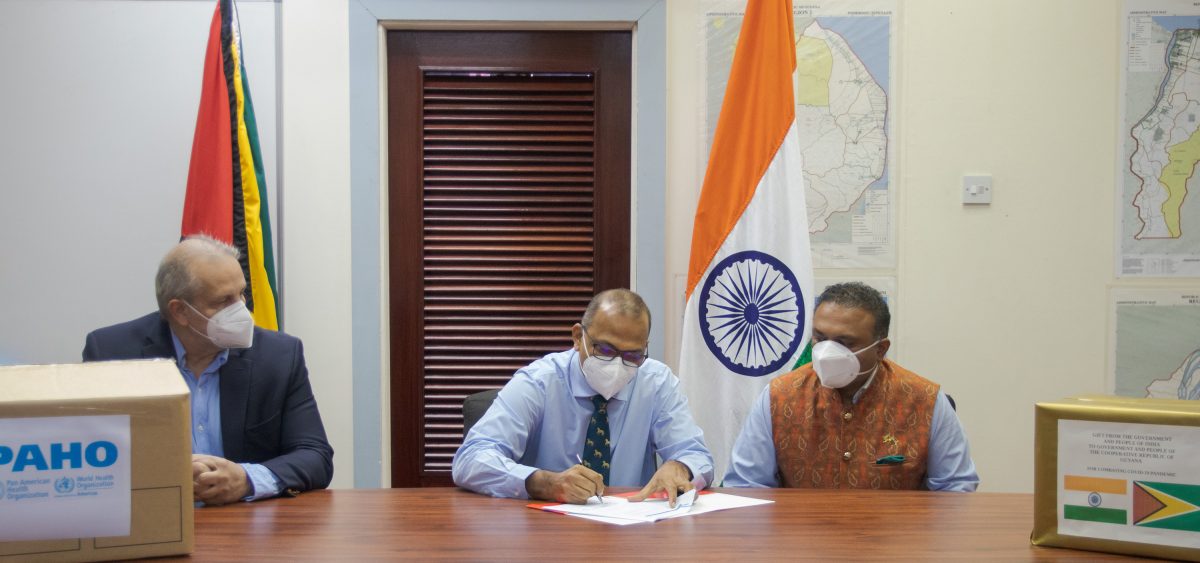 Minister of Health Dr Frank Anthony signs the close of project documents as , High Commission-er of India, Dr K.J. Srinivasa (at right) and PAHO/WHO Country Representative Dr Luis Codina look on