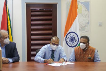 Minister of Health Dr Frank Anthony signs the close of project documents as , High Commission-er of India, Dr K.J. Srinivasa (at right) and PAHO/WHO Country Representative Dr Luis Codina look on