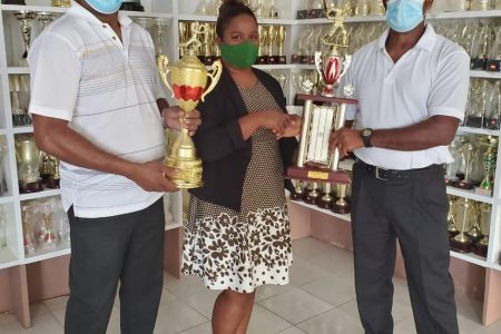 Rajin Moonsammy, right, receives the trophies from Chitra Bedessie in the presence of former national U19 cricketer Michael Chinsammy.