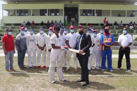 Minister of Natural Resources, Vickram Bharrat (in suit) hands over a cricket bat to Rampertab Ramnauth in the presence of the Berbice Under-19 squad (Romario Samaroo photo)