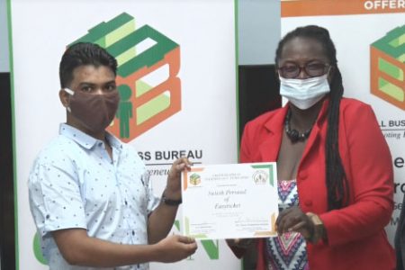 Satesh Persaud (left) being awarded with $1 million on Thursday by Yanessa Thompson, Deputy CEO of the Small Business Bureau, to fund his Green Business Technology strategy 
