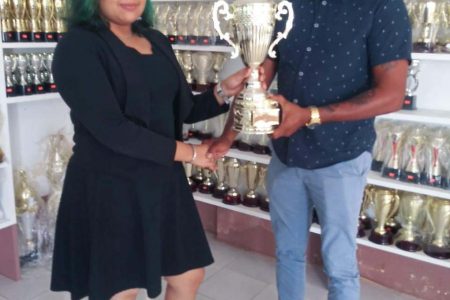 A representative of Trophy Stall’s Berbice branch, Aleena Asgarally, hands over the trophy to competition co-ordinator Roy Jafferally of the Grill Masters softball team.