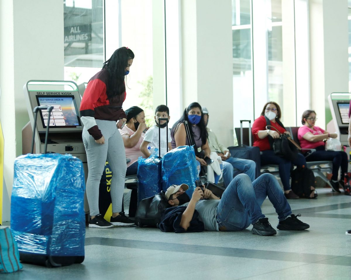 Venezuelan nationals wait at the check-in area at the Piarco International Airport after the repatriation flight was stopped yesterday.