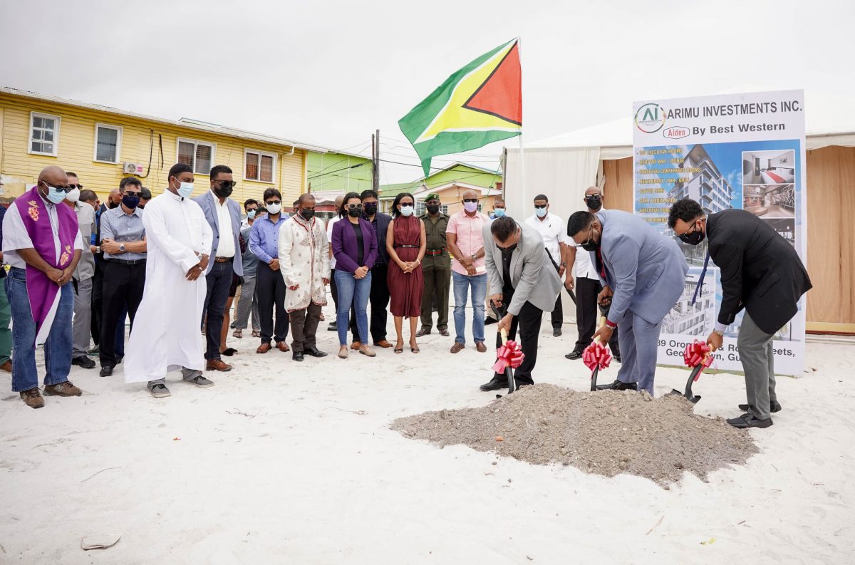 President Irfaan Ali [at centre), Chief Executive officer (CEO) of Go-Invest Peter Ramsaroop (at left ) and Co-Director of the Aiden Hotel Lorenzo Alphonso turning the sod as guests, including Minister of Tourism Oneidge Walrond, look on. (Office of the President photo)