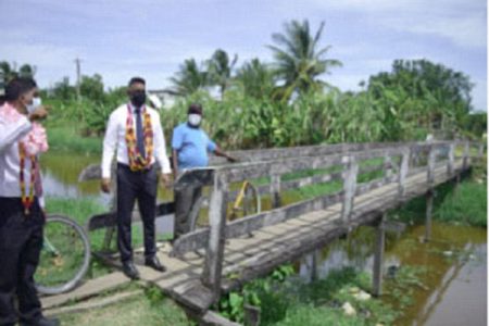 Minister within the Ministry of Public Works, Deodat Indar (second from left) stands near a dilapidated bridge in Enterprise which will soon undergo repairs. (Ministry of Public Works photo) 