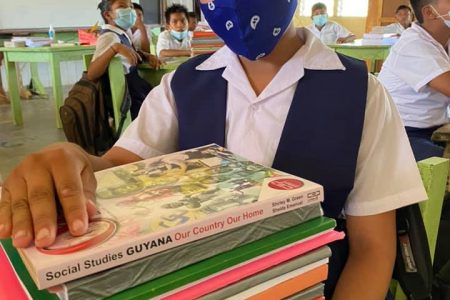 A student of the Aishalton Primary School in Region Nine along with her NGSA study package provided by the Ministry of Education.