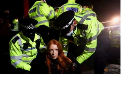 Police detain a woman as people gather at a memorial site in Clapham Common Bandstand, following the kidnap and murder of Sarah Everard, in London, Britain March 13, 2021. REUTERS/Hannah McKay