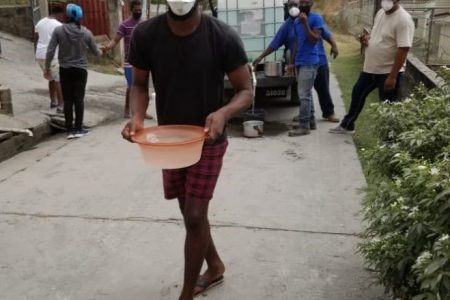 A man carries a container of water in Questelles, St Vincent, on Saturday, during a distribution of water in the area.