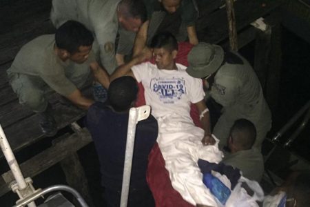 Members of the Guyana Defence Force and the Guyana Police Force assisting injured Lieutenant Edmundo Luis Berti Garcia into a boat as they prepared to transport him back to Venezuela.(Guyana Police Force photo)