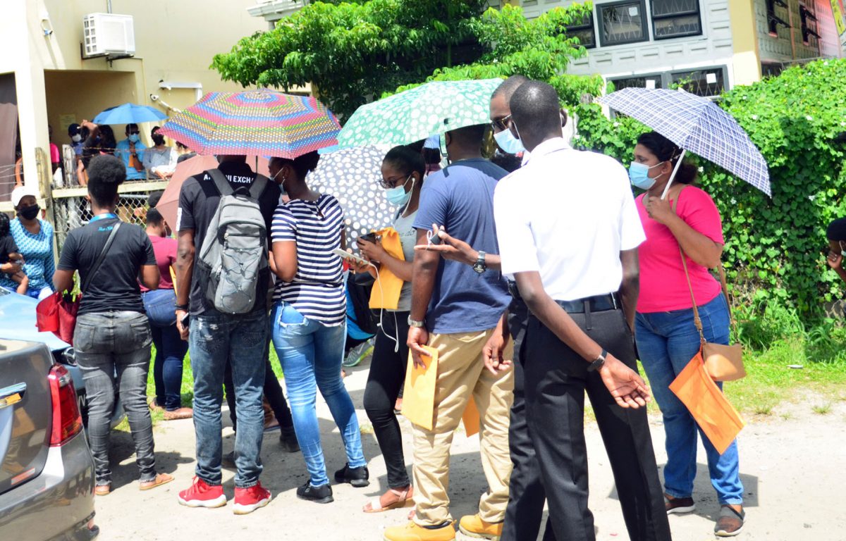 Persons waiting on the side of the road in front of the Central Passport and Immigration Office in Georgetown to submit their applications for a new passport (Orlando Charles photo)
