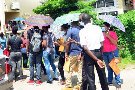 Persons waiting on the side of the road in front of the Central Passport and Immigration Office in Georgetown to submit their applications for a new passport (Orlando Charles photo)
