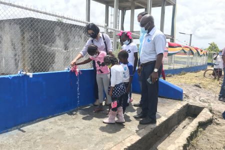 GWI recommissions Moblissa well: Minister Susan Rodrigues and children of Moblissa ceremonially turn on a standpipe at the well for the recommissioning of the community’s water supply system. 