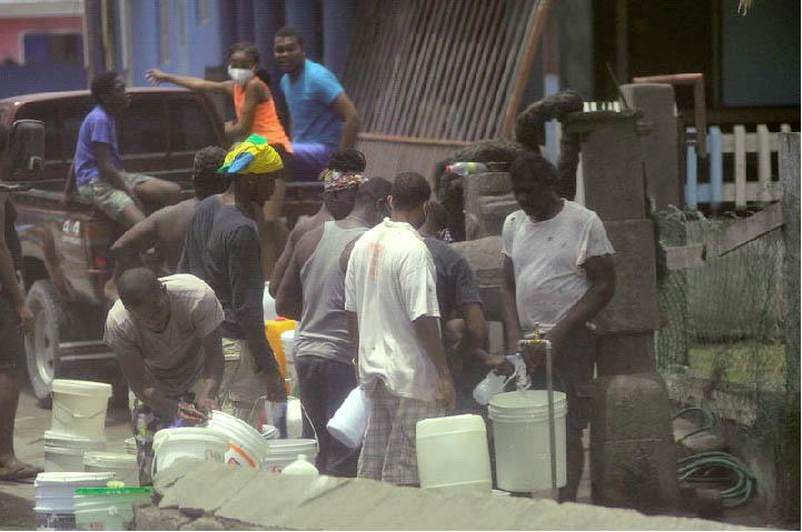 Local residents fill containers of water after a series of eruptions from La Soufriere volcano covered the area with a thick layer of ash in Biabou, Saint Vincent and the Grenadines, April 13, 2021. REUTERS/Robertson S. Henry