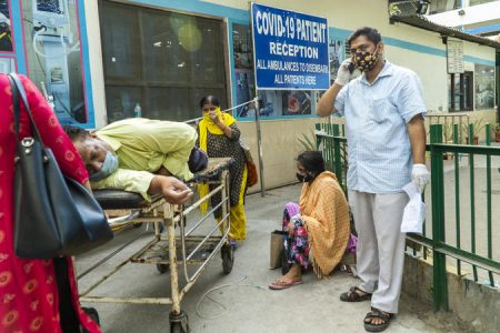 In this picture taken on April 23, 2021, relatives wait next to a Covid-19 coronavirus patient laying on a stretcher in a hospital complex for admission in New Delhi. Photo: AFP