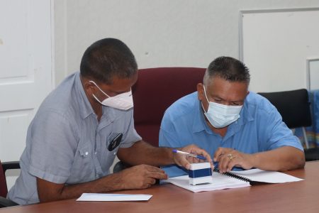 Denzil Roberts (right) and a representative of Doodnauth Construction and Supplies signing a contract (Ministry of Agriculture photo)