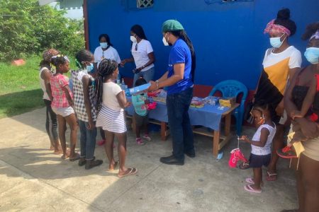 MP Jermaine Figueira (centre) distributing tablets, toys and other items to children at No. 28 Village. (PNCR photo)