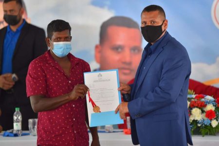 Minister of Housing and Water Collin Croal (right) with a Region Two resident who received his land title on Saturday. (Ministry of Housing and Water photo)