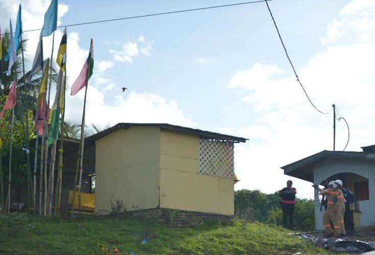 Scene of the accident: Police and employees of the Trinidad and Tobago Electricity Commission (T&Tec) at the scene of the incident where Ramnath Ramlochan was electrocuted yesterday afternoon after offering prayers while installing a jhandi near the prayer room in his yard at Charlo Village, SS Erin Road, Penal. —Photo: DEXTER PHILIP 