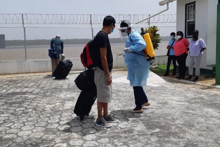 A traveller arriving from Suriname being sanitised after disembarking the MB Sandaka when the ferry service was resumed in February (Ministry of Public Works photo)