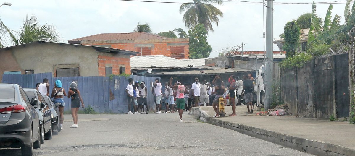 Party-goers at a private event at Production Drive, Sea Lots, stand along the roadway after they were warned by officers from the Port-of-Spain Division Task Force to disperse yesterday.