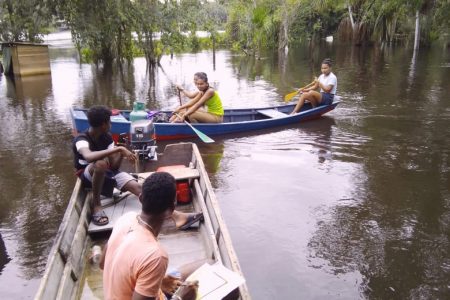 With large parts of Kwakwani still under water, persons are using boats to get about 