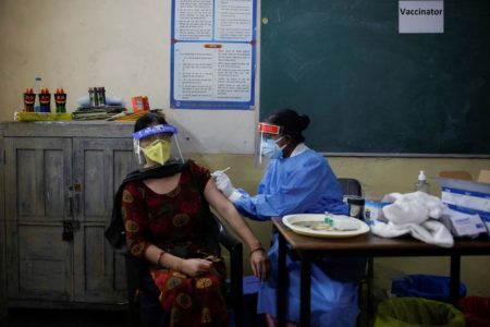 A healthcare worker gives a dose of COVISHIELD, a coronavirus disease (COVID-19) vaccine manufactured by Serum Institute of India, to a woman inside a classroom of a school, which has been converted into a temporary vaccination centre, in New Delhi, India, May 4, 2021. REUTERS/Adnan Abidi