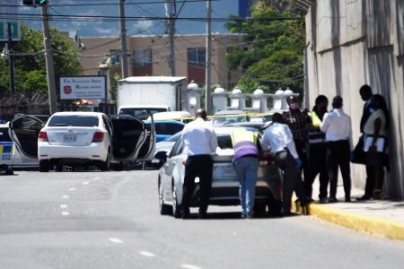 Investigators huddle along Trafalgar Road after police engaged gunmen in a fire fight on Monday. Two men were killed in the incident.