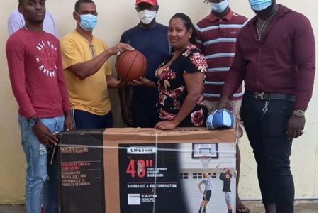 Clement Munroe (third from left) presents the basketballs and backboard to  the secretary of the Rose Hall Town Jammers in the presence of club players and the president of the BABA Vibert Garrett (centre).