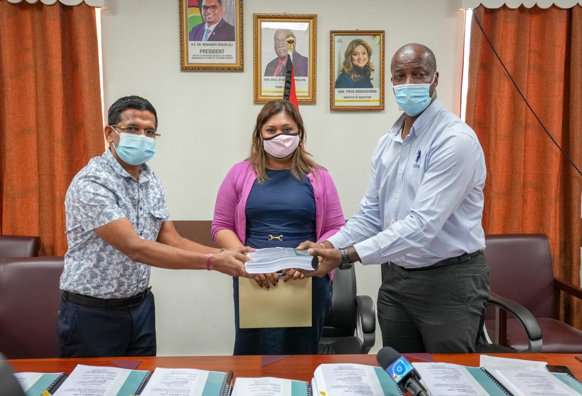 Permanent Secretary, Alfred King (right) receiving one of the signed documents today from the contractor in the presence of the Minister of Education Priya Manickchand. (Ministry of Education photo)
