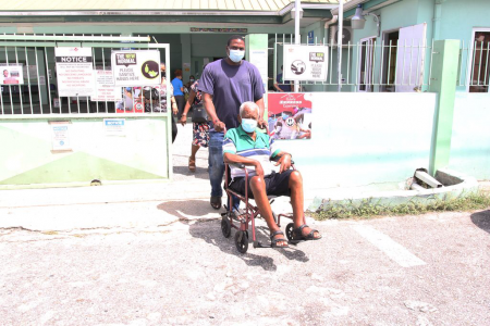 A man being wheel out of the Barataria Health Centre in his wheelchair by a family member after getting the second jab of the COVID-19 vaccine yesterday.