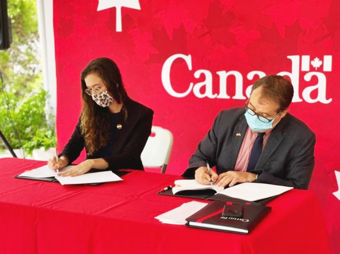 Canada’s High Commissioner Mark Berman (right) and Country Manager for HIAS Guyana, Alex Theran signing the document. (Canadian High Commission photo)