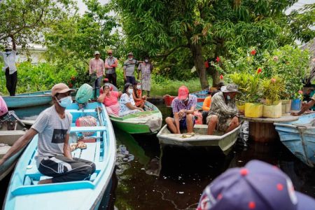They came in boats: Flooded Mahaica residents in their boats waiting to listen to President Irfaan Ali yesterday.  (Office of the President photo)