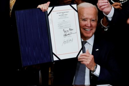 U.S. President Joe Biden is applauded as he holds the Juneteenth National Independence Day Act during a signing ceremony in the East Room of the White House in Washington, U.S., June 17, 2021. REUTERS/Carlos Barria