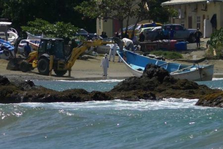 FLASHBACK: A backhoe pulls the boat on which 14 bodies were found ashore at Back Bay, Belle Gardens, Tobago.