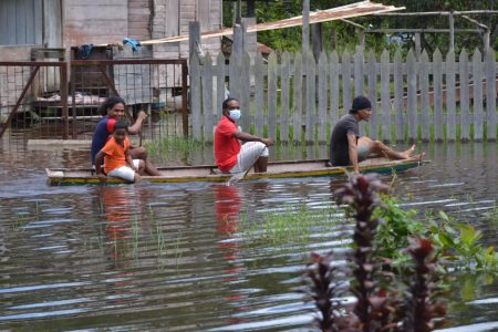 Persons traveling by boat in one of the flooded riverine communities in Region Ten. (Photo taken from Nigel Dharamlall’s Facebook page) 