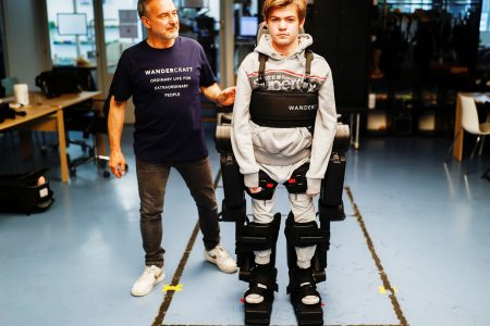 Jean-Louis Constanza, Chief Business and Clinical Officer at French company Wandercraft helps his 16-year-old son Oscar using a robot exoskeleton at the company headquarters in Paris, France July 9, 2021. Picture taken July 9, 2021. (REUTERS/Christian Hartmann photo) 