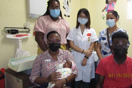 Fiona Jones (seated with baby) and her husband Simon Jones (seated at right) along with the Paediatric team (from left), Dr. Teani Small, Dr. Wang Xuli and Dr. Barker. (Linden Hospital Complex photo)
