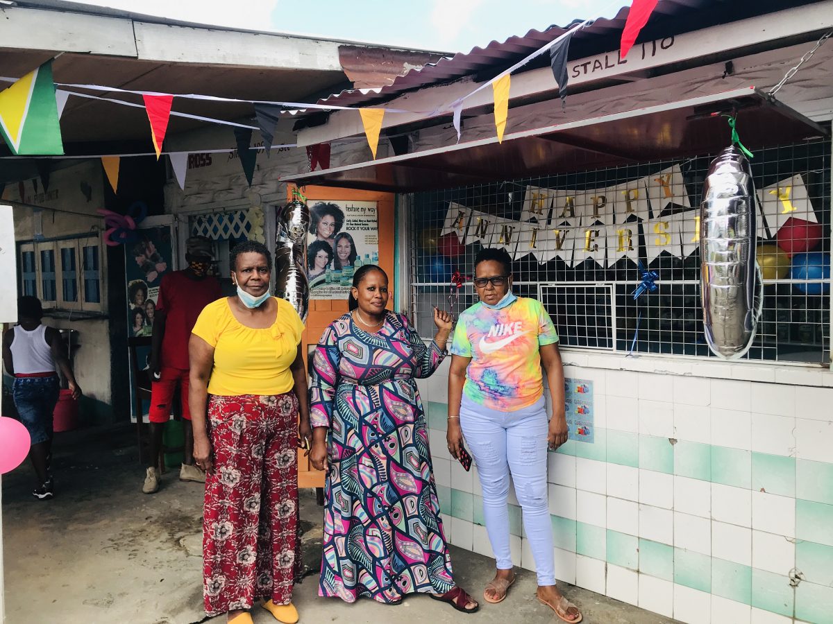 Three vendors posing in front of a decorated stall 