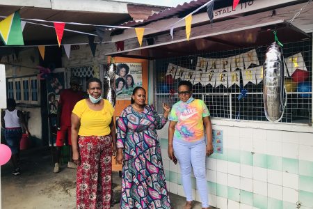 Three vendors posing in front of a decorated stall 