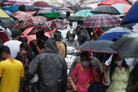 FILE PHOTO: A woman rides a scooter through a crowded market on a rainy day amidst the spread of the coronavirus disease (COVID-19) in Mumbai, India, July 14, 2021. REUTERS/Francis Mascarenhas