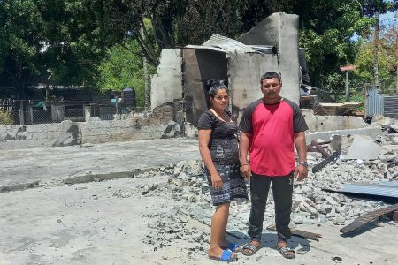 Taramattie Abrahim and her husband, Rajkumar Hemnauth, stand amidst the remnants of their destroyed home