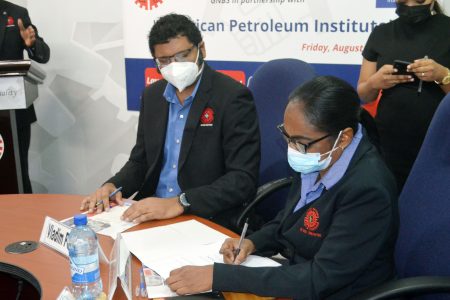 Ramrattie Karan (at right) signing the MoU (Orlando Charles photo) 