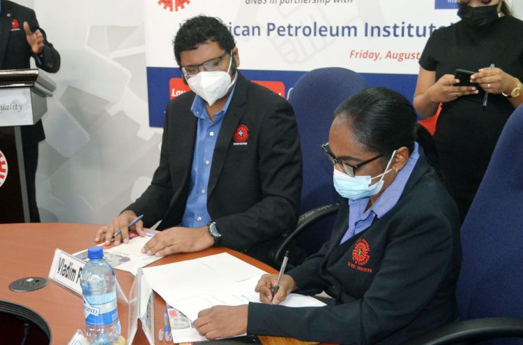 Ramrattie Karan (at right) signing the MoU (Orlando Charles photo) 