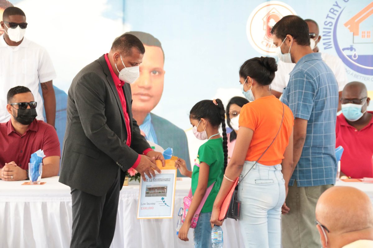 Luck of the draw: A young girl pulls a lot number from an envelope held by Minister of Housing Collin Croal for a low income house lot for her family at the fifth ‘Dream Realised’ housing drive that was held yesterday at the Arthur Chung Conference Centre (CH&PA photo) 